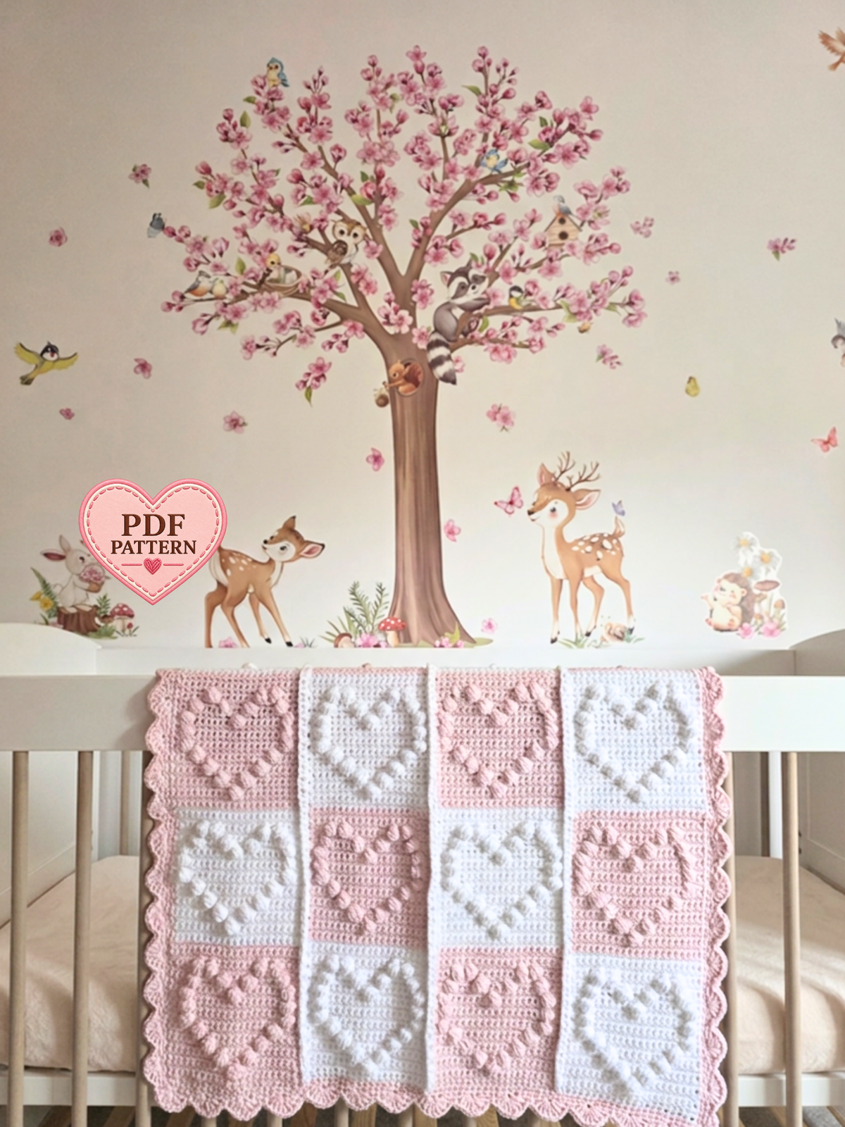 A handmade crochet baby blanket with a patchwork design of pink and white squares with large hearts.