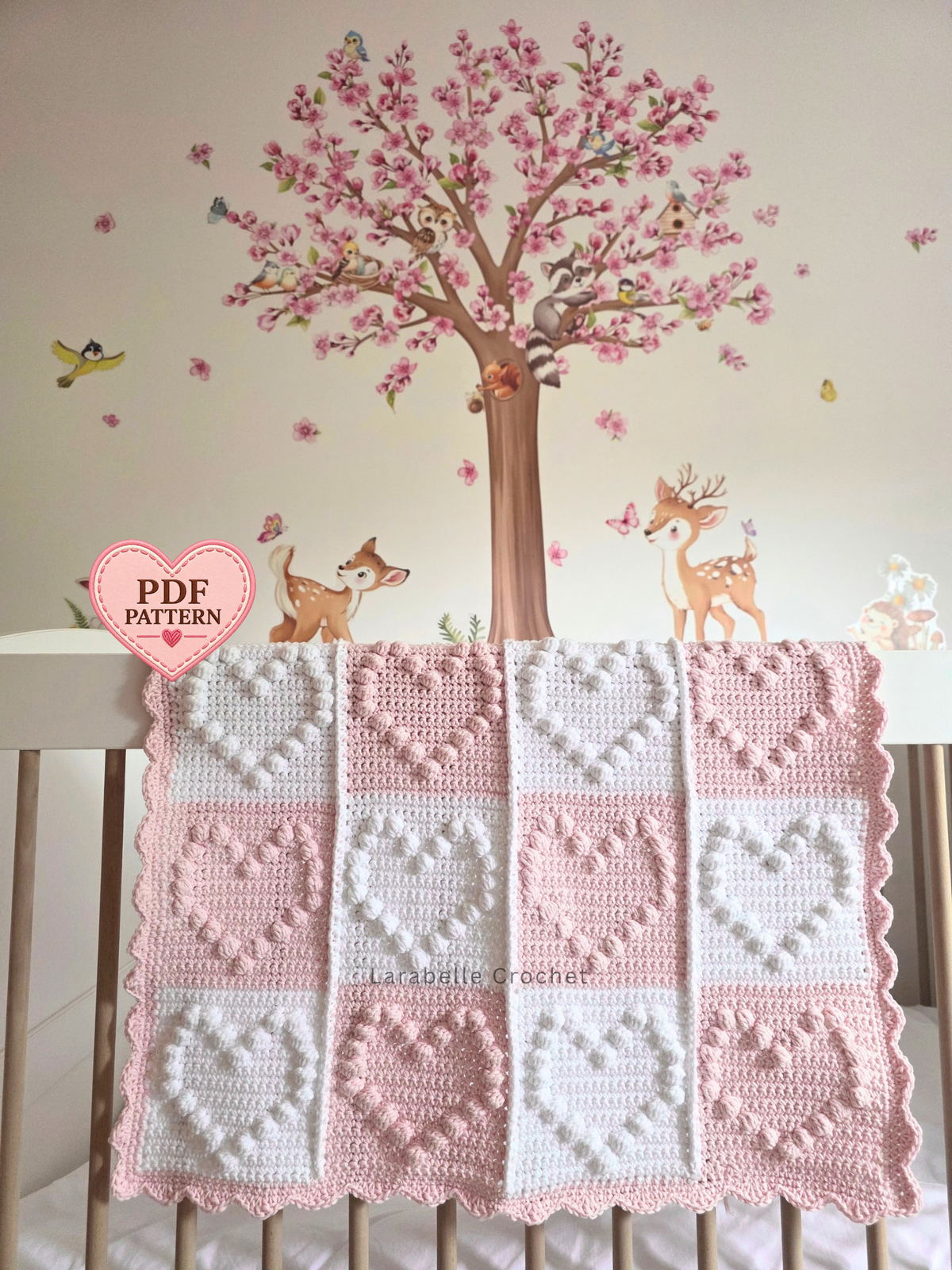 A handmade crochet baby blanket with a patchwork design of pink and white squares with large hearts.