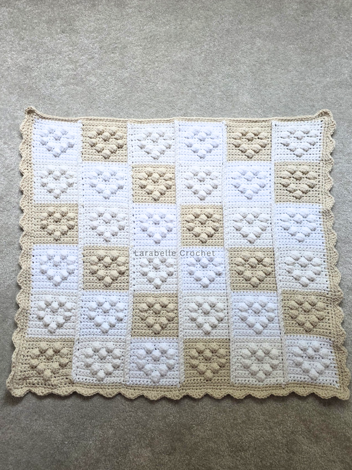 Full view of crochet baby blanket featuring small hearts in a patchwork grid of 6 x 6.