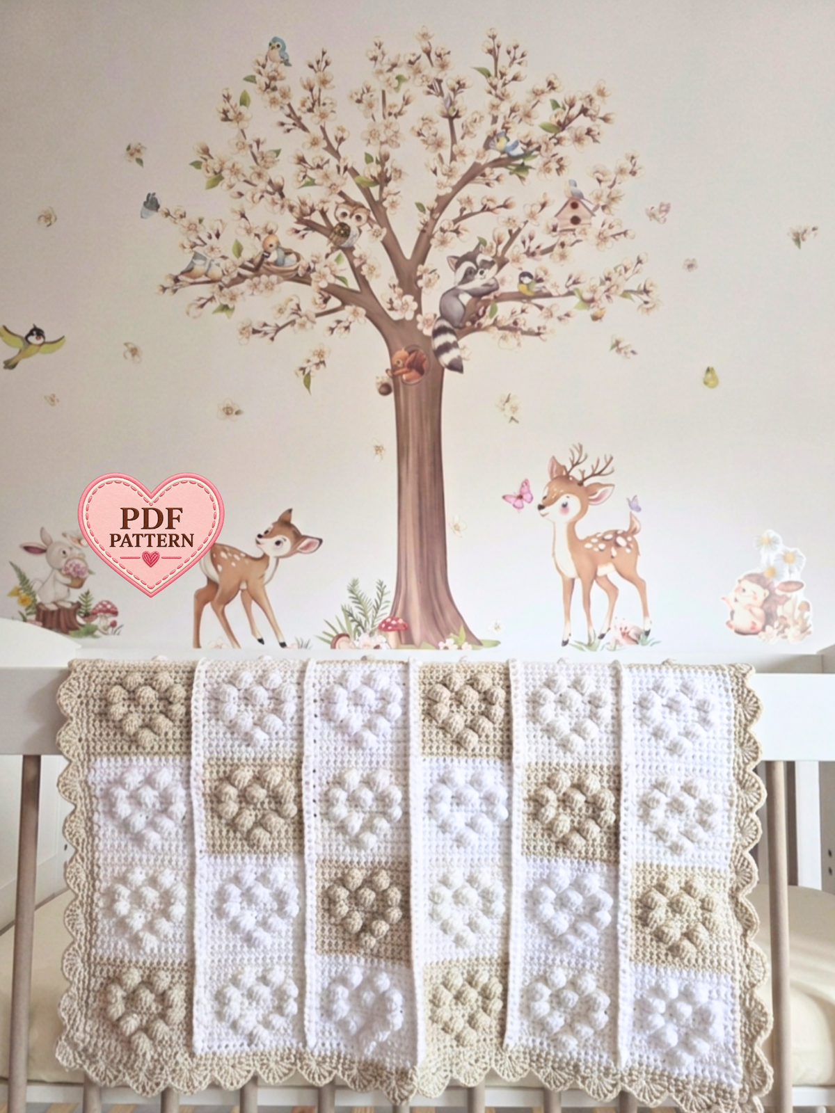 A handmade crochet baby blanket with a patchwork design of cream, beige, and white squares with small hearts.