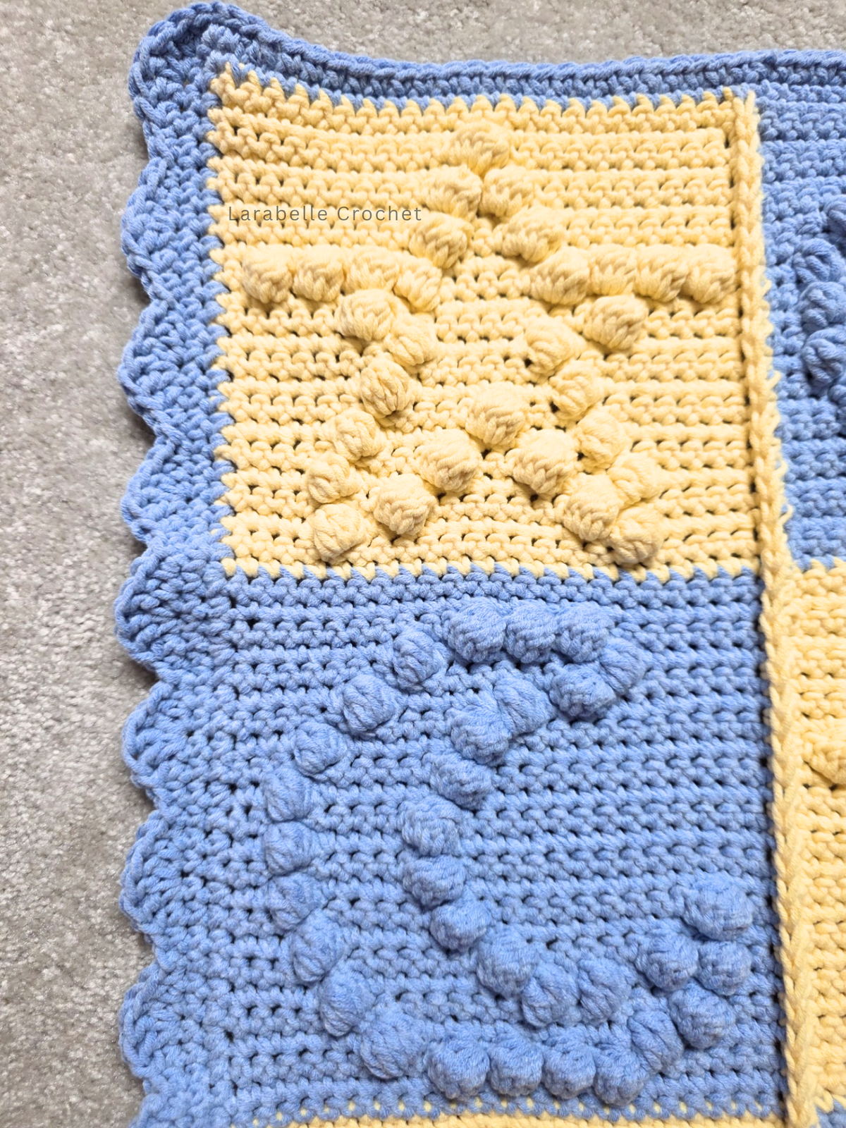 Close up view of crochet baby blanket featuring stars and moons in a patchwork grid of 6 x 6.
